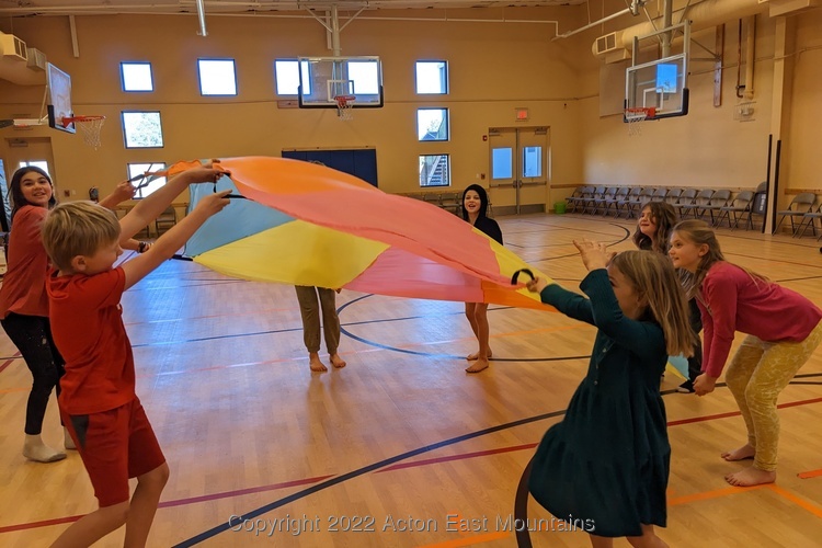 Learners at Acton Academy East Mountains outdoor-centric private school near Albuquerque, New Mexico playing cooperatively with a 'parachute'. 