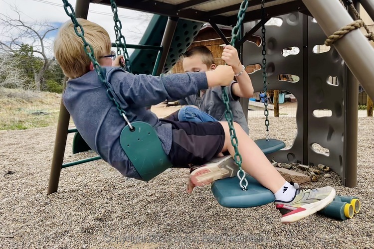 Learners at Acton Academy East Mountains private school near Albuquerque, New Mexico playing on swings.